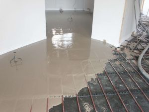 Cemex Supaflo liquid screed starting to flow into the area. As the floor screed is liquid it completely encases the pipework, and by eliminating air pockets found in conventional sand/cement screed increases the efficiency of the underfloor heating system.