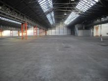 Surveying an industrial unit floor that needs restoration and repair by means of re-screeding.