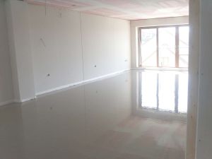 The finished floor, note the reflection of the ceiling and patio door on the smooth mirror-like finish of the floor screed prior to drying.